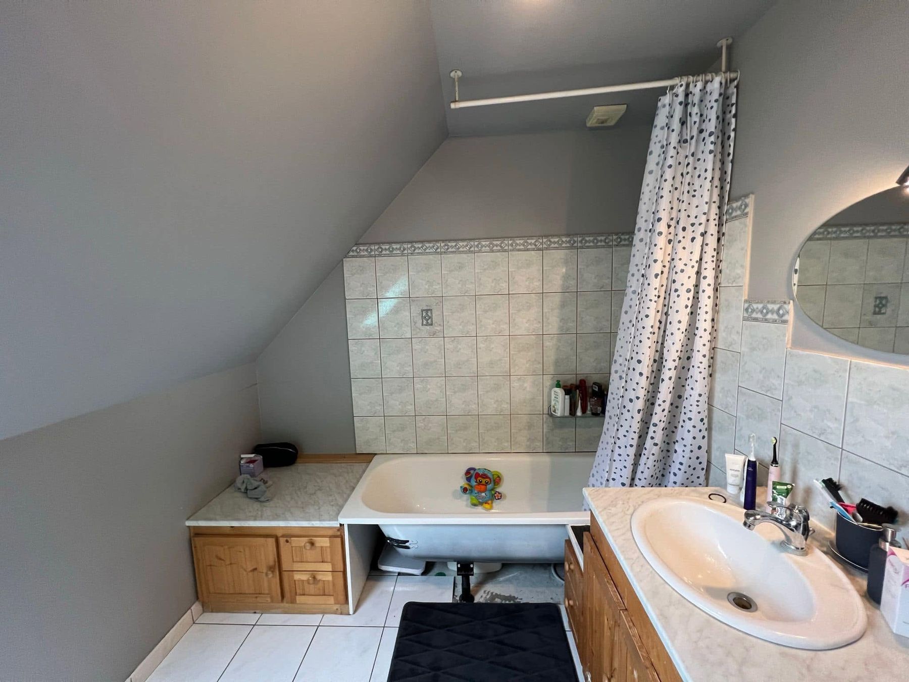 Salle de bain avant travaux : ancienne baignoire, carrelage et meuble en bois